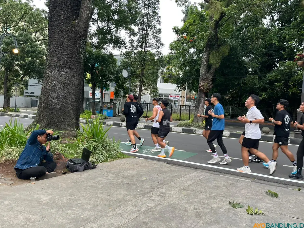 Seorang fotografer mengabdikan para pelari di daerah Dago, Kota Bandung. (Sumber: ayobandung.id | Foto: Ilham Maulana)