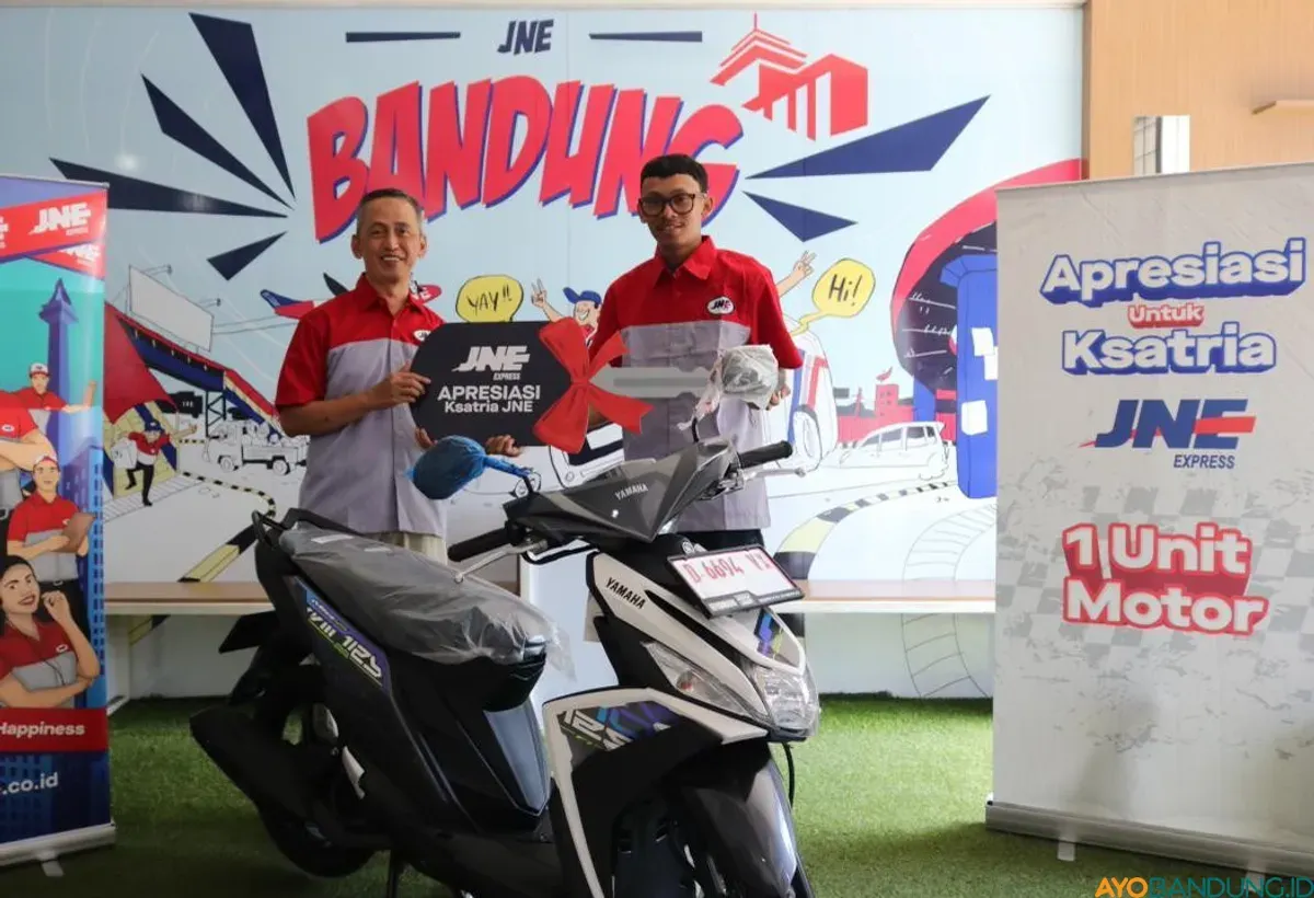 Kepala Cabang Utama JNE Bandung Iyus Rustandi menyerahkan bantuan sepeda motor baru kepada Hasan sebagai bentuk nyata komitmen dan kepedulian perusahaan terhadap keselamatan karyawannya. (Sumber: ayobandung.id | Foto: Arif Budianto)