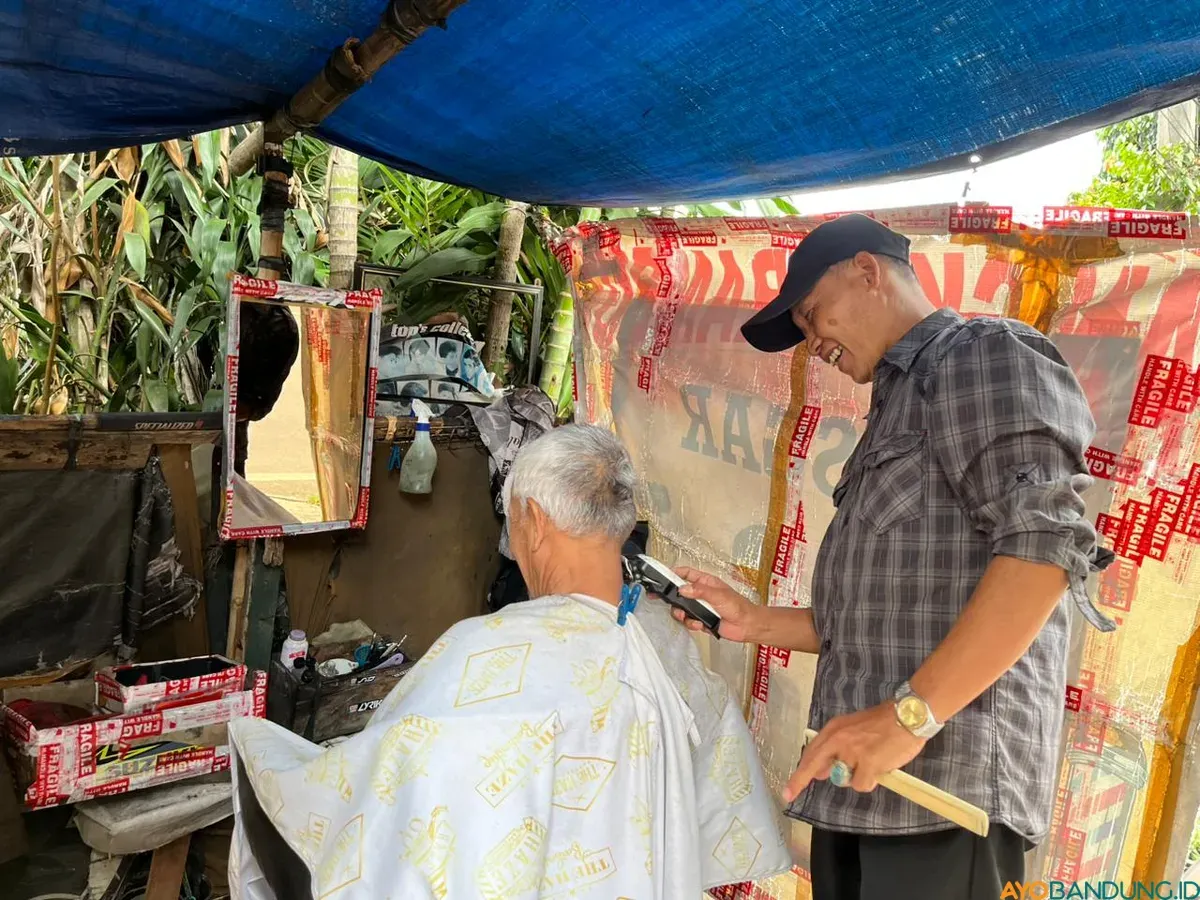 Yana Mulyana dengan ruang ala kadarnya tetap bertahan di bawah rindang pohon Jalan Malabar, Kota Bandung. (Sumber: ayobandung.id | Foto: Ilham Maulana)