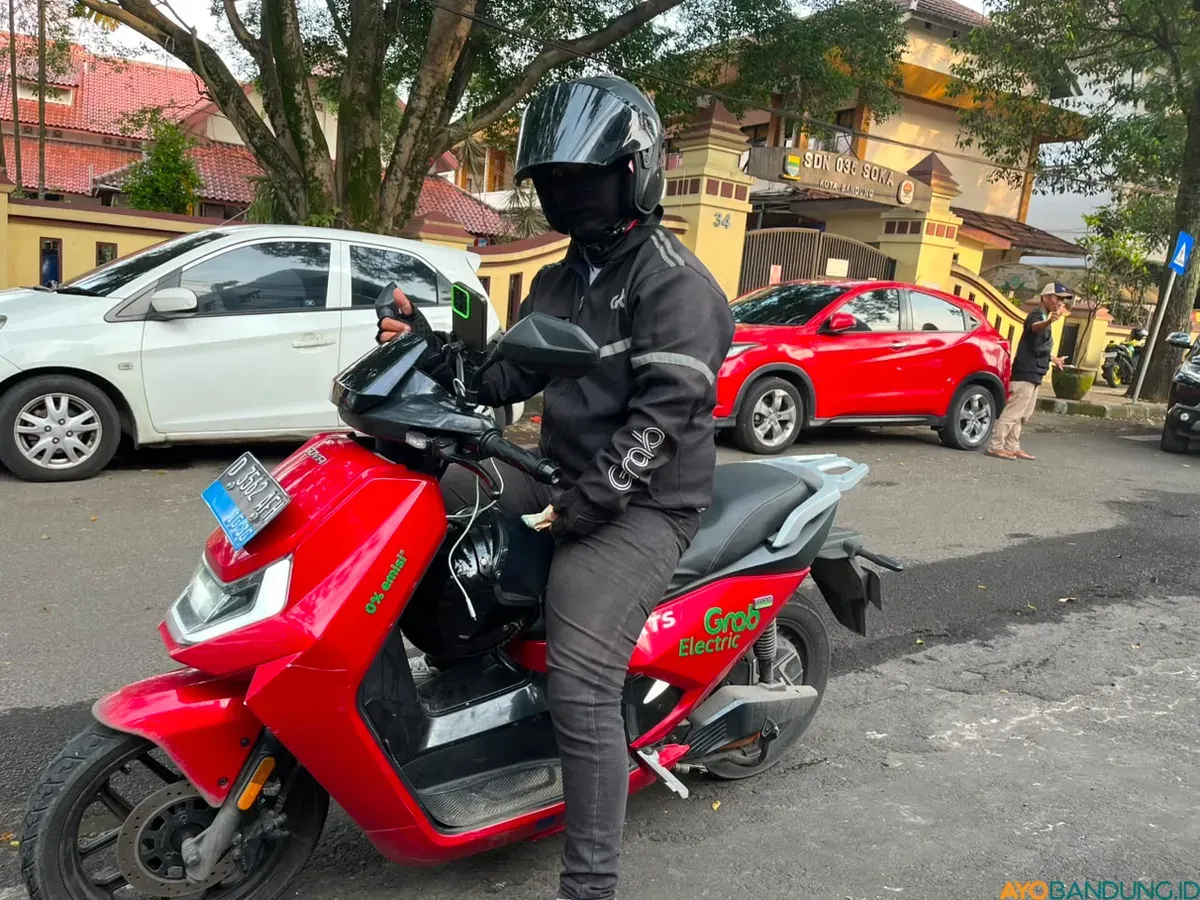 Yusuf dan motor listriknya yang digunakannya untuk mengantar penumpang di kawasan Kota Bandung. (Sumber: ayobandung.id | Foto: Ilham Maulana)