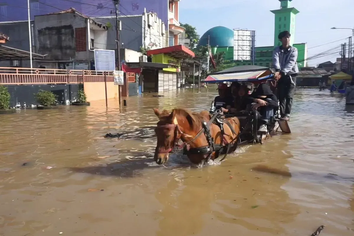 Warga memanfaatkan delman untuk melintasi jalan permukiman yang terendam banjir, saat akses kendaraan bermotor terganggu akibat genangan air. (Sumber: Dokumentasi Warga | Foto: Dokumentasi Warga)