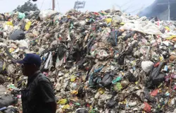 Warga melintas di depan tumpukan sampah di TPS Pasar Ciwastra, Kota Bandung, Selasa 22 April 2025. Penumpukan tejadi diakibatkan pembatasan pembuangan sampah ke TPA Sarimukti. (Sumber: Ayobandung | Foto: Irfan Al Faritsi)