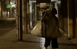 Seorang tunawisma menyusuri lorong Pasar﻿ pada malam hari (29/10/25) dengan memanggul karung besar di Jln. ABC, Braga, Sumur Bandung, Kota Bandung. (Foto: Rajwaa Munggarana)