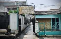 Akses masuk SDN 117 Batununggal yang terlihat sepi usai hujan menyisakan genangan air di area jalan masuk, Kecamatan Batununggal, Kota Bandung. (4/12/2025) (Sumber: Raveyfa Shinta | Foto: Raveyfa Shinta)