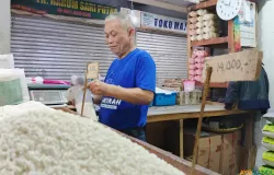 Rahmat Kurnia (52) tengah menyiapkan sekantong plastik beras untuk pembeli di Pasar Kosambi, Kota Bandung. (Sumber: ayobandung.id | Foto: Gilang Fathu Romadhan)