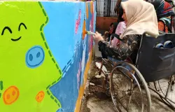Elis sedang mewarnai mural dengan kuas di tangan kirinya. (Sumber: Ayobandung | Foto: Gilang Fathu Romadhan)