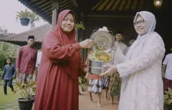 Proses tradisi nganteuran. Ibu Indah (kanan) membawa rantang berisi hidangan Lebaran dan menyerahkannya kepada Ibu Lilis di Kampung Sukabirus, Desa Citeureup, Kecamatan Dayeuhkolot, Kabupaten Bandung (20/03/25). (Sumber: Lilis Sekar Sari)