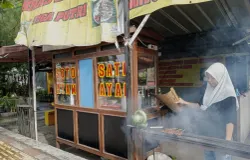 Yana, putri sulung keluarga Mustofa, sibuk memanggang sate ayam di depan kedai Soto dan Sate Ayam Khas Madura. (Foto: Syahiratul Mghfiroh)
