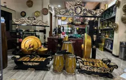 Pengrajin Giri Purwa Seni menampilkan seperangkat alat musik tradisional berwarna keemasan di ruang pamer Giri Purwa Seni, Jl. Soekarno Hatta No. 425, Desa Cigereleng, Astana Anyar, Karasak, pada Senin, 10 November 2025. (Sumber: Dokumentasi Penulis)