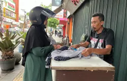 Pelanggan sedang berbincang dengan Andi untuk memperbaiki pakaiannya di kawasan Kosambi, Kota Bandung. (Sumber: ayobandung.id | Foto: Ilham Maulana)