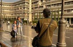 Wisatawan lokal berpose di Jalan Asia Afrika Kota Bandung dengan latar belakang gedung bersejarah, Hotel Savoy Homann. (Sumber: ayobandung.id | Foto: Ilham Maulana)