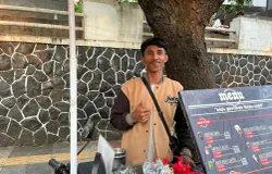 Penjual kopi keliling, Fandi Ginanjar, melayani pembeli dengan memanfaatkan sepeda listrik hasil modifikasi. (Sumber: ayobandung.id | Foto: Ilham Maulana)