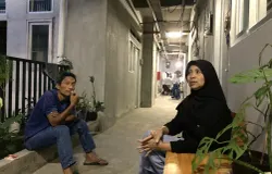 Wawan (duduk) di lorong rumah deret Tamansari, ia berusaha bertahan dengan pekerjaan serabutan di tengah perubahan hidup pascarelokasi. (Sumber: ayobandung.id | Foto: Halwa Raudhatul)