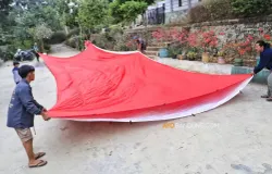 Warga membentangkan bendera Merah Putih raksasa berukuran 10x18 meter sebagai persiapan pengibaran pada 17 Agustus 2026 di Tebing Gunung Hawu. (Sumber: Ayobandung.com | Foto: Irfan Al-Faritsi)