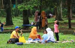 Warga memanfaatkan ruang terbuka hijau di Kebun Binatang Bandung untuk bersantai dan makan bersama. (Sumber: ayobandung.id | Foto: Irfan Al Faritsi)