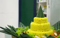 Tumpeng nasi kuning berdiri gagah dikelilingi berbagai lauk pauk dalam acara syukuran keluarga. (Sumber: Unsplash | Foto: Deski Jayantoro)
