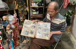 Tatang Heriana mengenang ayah dan masa mudanya lewat album foto yang masih hitam putih. (Sumber: ayobandung.id | Foto: Halwa Raudhatul)