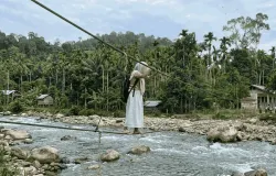 Seorang anak sekolah di Aceh yang menyebrangi jembatan tali menuju sekolah. (Sumber: Generated AI (Terinspirasi dari Video Asli di Aceh))