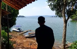 Siluet dari Ilham Fadilah, Direktur BUMDes Cisurat, di tepian Waduk Jatigede, Kecamatan Wado, Kabupaten Sumedang, (11/6/2026). (Sumber: Ayobandung.id | Foto: Aris Abdulsalam)