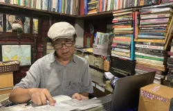 Pendiri Perpustakaan Batu Api, Anton Solihin, duduk di tengah tumpukan buku koleksi pribadinya. (Sumber: ayobandung.id | Foto: Halwa Raudhatul)