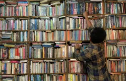Seorang pengunjung mencari buku di antara rak-rak sempit Perpustakaan Batu Api, Jatinangor, Sabtu 9 Mei 2026. (Sumber: ayobandung.id | Foto: Halwa Raudhatul)