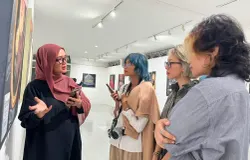 Ima Suswanto menjelaskan makna di balik salah satu karya yang dipamerkan dalam pameran NeoFemisida kepada pengunjung. (Sumber: ayobandung.id | Foto: Ilham Maulana)