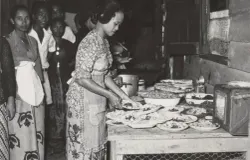 Sebuah foto yang memperlihatkan seorang perempuan Jawa di Suriname sedang menyiapkan hidangan ala Jawa untuk sebuah perjamuan. (Sumber: collectie.wereldmuseum.nl)