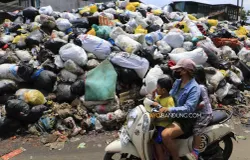 Pengendara melintas di dekat tumpukan sampah yang menggunung di TPS Jalan Makam Caringin, Kota Bandung, Kamis, 9 April 2026. (Sumber: Ayobandung | Foto: Irfan Al-Faritsi)