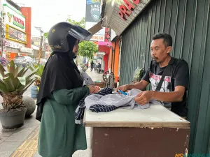 Pelanggan sedang berbincang dengan Andi untuk memperbaiki pakaiannya di kawasan Kosambi, Kota Bandung. (Sumber: ayobandung.id | Foto: Ilham Maulana)