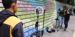 Konten kreator TikTok bernyanyi secara daring menggunakan smartphone (telepon pintar) di Jalan Babakan Siliwangi, Kota Bandung (Sumber: Ayobandung.com | Foto: Irfan Al-Faritsi)