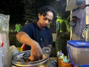 Berjualan cilok menjadi sumber penghasilan utama Raja, di sela kegiatannya mengelola lapak baca sederhana di pinggir jalan. (Sumber: ayobandung.id | Foto: Ilham Maulana)