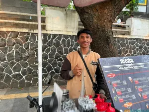 Penjual kopi keliling, Fandi Ginanjar, melayani pembeli dengan memanfaatkan sepeda listrik hasil modifikasi. (Sumber: ayobandung.id | Foto: Ilham Maulana)