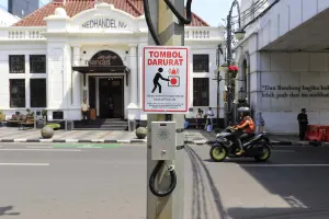 Pengguna jalan melintas di dekat satu tombol darurat (panic button) yang dipasang di Jalan Asia Afrika, Kota Bandung, Rabu 26 November 2025. (Sumber: Ayobandung.id | Foto: Irfan Al-Faritsi)