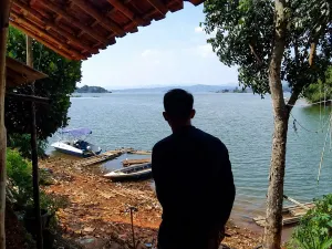Siluet dari Ilham Fadilah, Direktur BUMDes Cisurat, di tepian Waduk Jatigede, Kecamatan Wado, Kabupaten Sumedang, (11/6/2026). (Sumber: Ayobandung.id | Foto: Aris Abdulsalam)