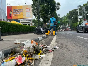 Sampah botol plastik, sisa makanan, dan bekas flare terlihat berserakan di sejumlah ruas jalan Kota Bandung selepas konvoi Persib. (Sumber: ayobandung.id | Foto: Ilham Maulana)