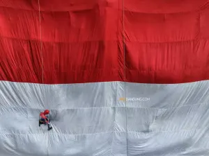 Pegiat panjat tebing berkostum spiderman mengibarkan bendera Merah Putih raksasa di Tebing Hawu, Kampung Cidadap, Desa Padalarang, Kecamatan Padalarang, Kabupaten Bandung Barat, Senin 17 Agustus 2026. (Sumber: Ayobandung | Foto: Irfan Al-Faritsi)