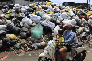 Pengendara melintas di dekat tumpukan sampah yang menggunung di TPS Jalan Makam Caringin, Kota Bandung, Kamis, 9 April 2026. (Sumber: Ayobandung | Foto: Irfan Al-Faritsi)