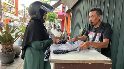 Pelanggan sedang berbincang dengan Andi untuk memperbaiki pakaiannya di kawasan Kosambi, Kota Bandung. (Sumber: ayobandung.id | Foto: Ilham Maulana)