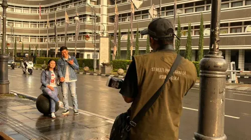 Wisatawan lokal berpose di Jalan Asia Afrika Kota Bandung dengan latar belakang gedung bersejarah, Hotel Savoy Homann. (Sumber: ayobandung.id | Foto: Ilham Maulana)