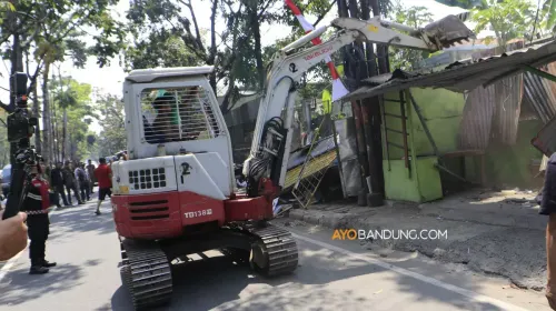 Petugas Satpol PP Kota Bandung menggunakan alat berat merobohkan bangunan liar dan lapak PKL di Jalan Ibrahim Adjie, Kiaracondong, Kota Bandung, Senin 10 Agustus 2026. (Sumber: ayobandung.com | Foto: Irfan Al-Faritsi)