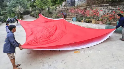Warga membentangkan bendera Merah Putih raksasa berukuran 10x18 meter sebagai persiapan pengibaran pada 17 Agustus 2026 di Tebing Gunung Hawu. (Sumber: Ayobandung.com | Foto: Irfan Al-Faritsi)