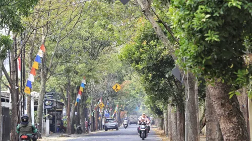 Pengendara melintasi jalan Pacuan Kuda Arcamanik pada Rabu, 19 Agustus 2026. Tampak jalan tersebut teduh karena masih ditumbuhi pohon-pohon berukuran besar. (Sumber: ayobandung.id | Foto: Irfan Al Faritsi)
