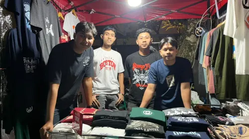 Jujun melayani pembeli di lapak kaos di Jalan Trunojoyo, Kota Bandung, saat mencoba peruntungan berjualan untuk pertama kali menjelang Lebaran dengan menawarkan promo dua kaos seharga Rp100 ribu. (Sumber: ayobandung.id | Foto: Ilham Maulana)