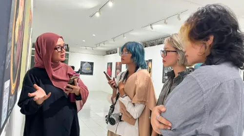 Ima Suswanto menjelaskan makna di balik salah satu karya yang dipamerkan dalam pameran NeoFemisida kepada pengunjung. (Sumber: ayobandung.id | Foto: Ilham Maulana)