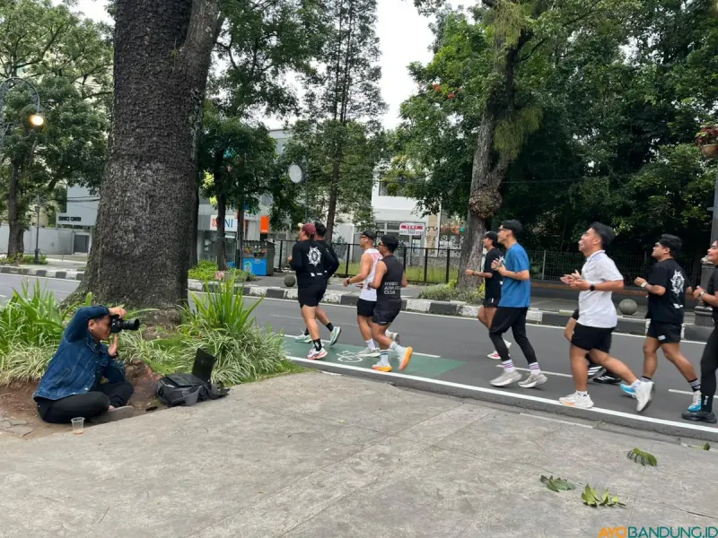 Seorang fotografer mengabdikan para pelari di daerah Dago, Kota Bandung. (Sumber: ayobandung.id | Foto: Ilham Maulana)