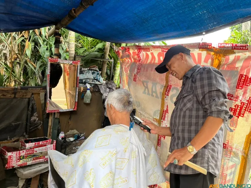 Yana Mulyana dengan ruang ala kadarnya tetap bertahan di bawah rindang pohon Jalan Malabar, Kota Bandung. (Sumber: ayobandung.id | Foto: Ilham Maulana)